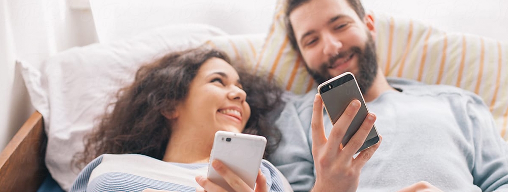 Yatakta tinder kullanan çift fotoğrafı.